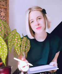 a woman holding a tablet with a plant in front of it